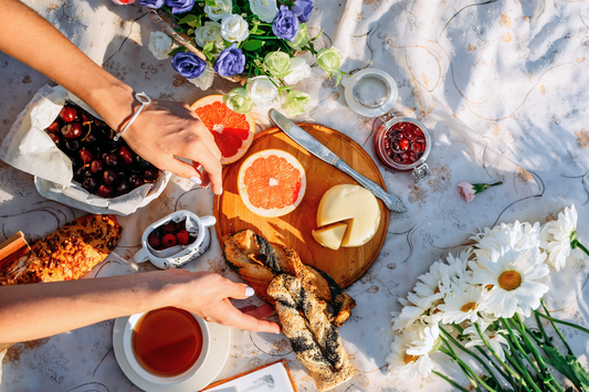 Floral brunch spread with fresh fruits, cheese, tea, and bread — summer tea pairing inspiration under sunlight