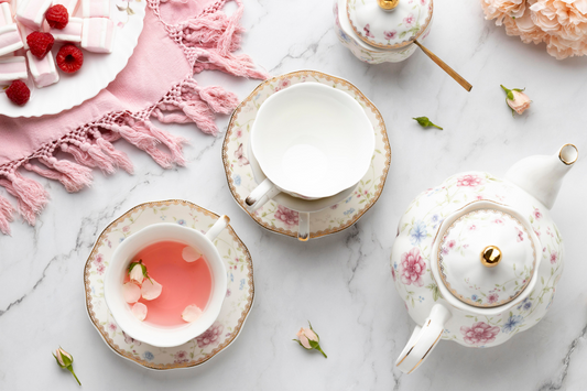 A beautifully styled tea scene featuring rose tea in porcelain cups, surrounded by rosebuds, marshmallows, and raspberries on a marble surface—perfect for a calming, elegant moment.