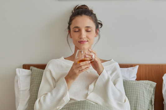 Woman peacefully sipping tea in bed, highlighting tea as part of a calming bedtime ritual for emotional balance