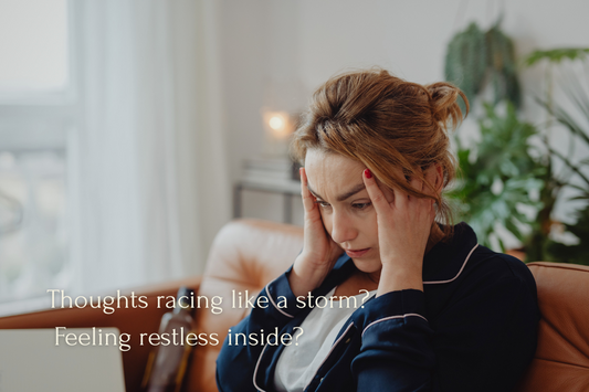 Woman sitting on couch with hands on her head, looking overwhelmed and stressed with racing thoughts.